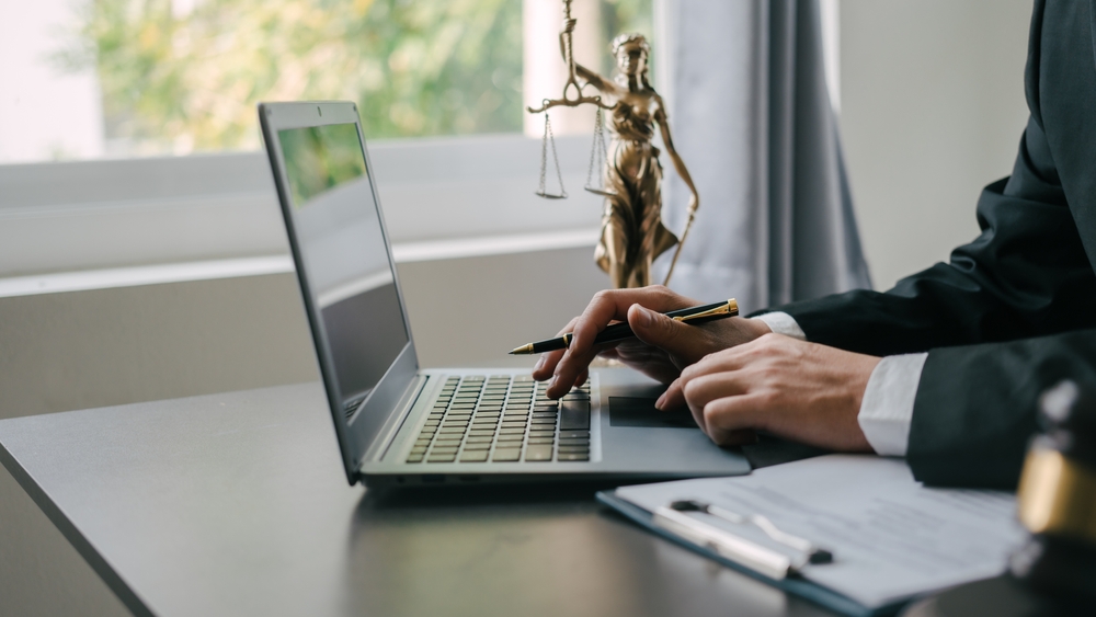 a lawyer using a laptop on a table with the justice statue